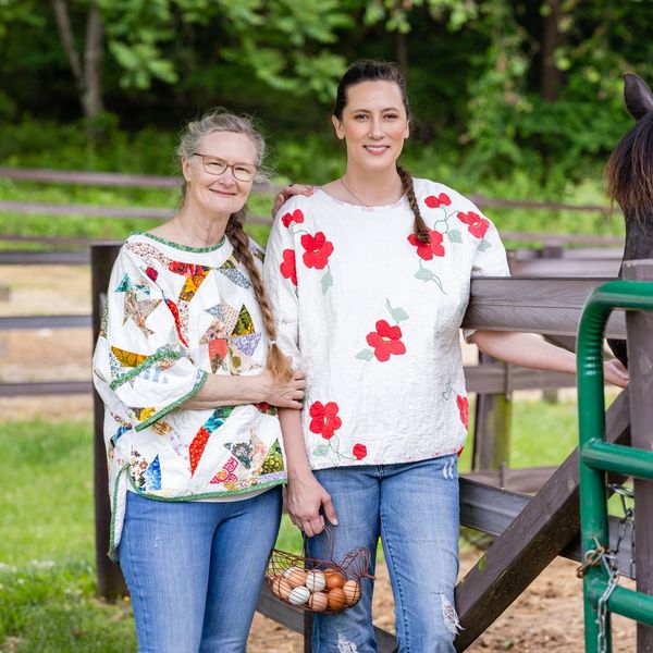 Two girls standing together with a horse