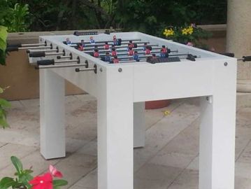 White foosball table set outdoors with red and blue players.