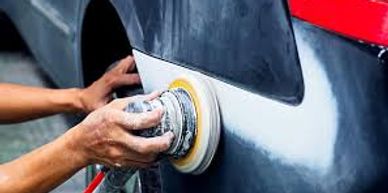 Person using a power sander on a car's body panel.