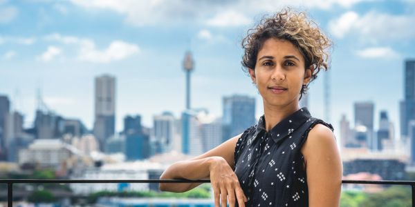 Confident and approachable team member standing on a balcony with the city skyline in the background, symbolizing our firm's forward-thinking and inclusive approach