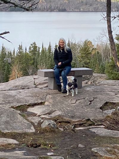Woman sitting on a bench with her dog over looking a beautiful lake. 