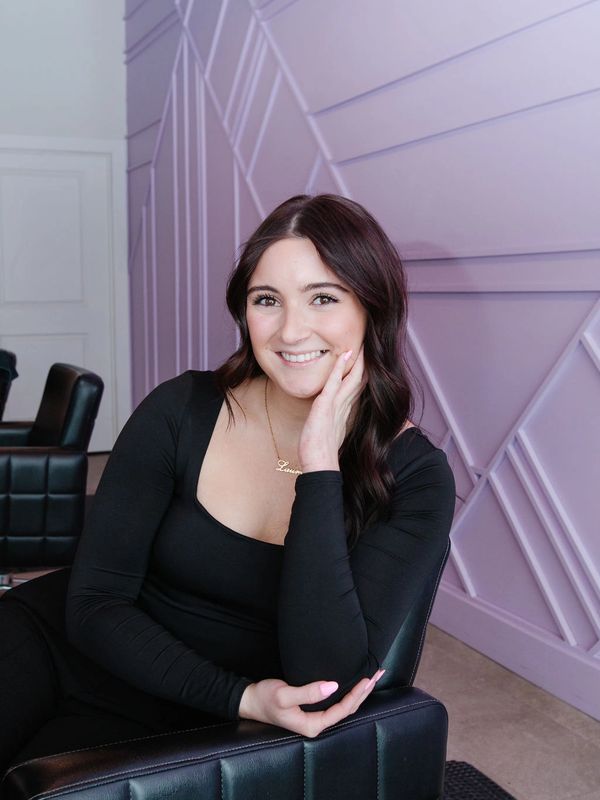 Woman in black sitting on a chair, smiling.