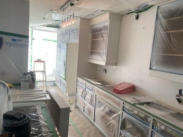 Kitchen under renovation with cabinets masked for painting.