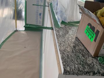 Kitchen countertop protected with plastic and tape for renovation work.