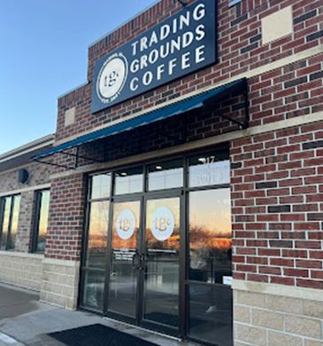 Exterior view of Trading Grounds Coffee shop with brick facade and glass doors.