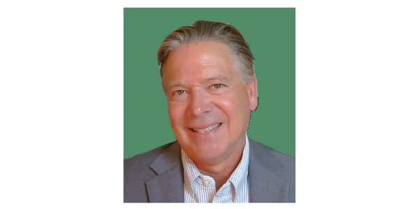 Smiling middle-aged man in a gray blazer against a green background.