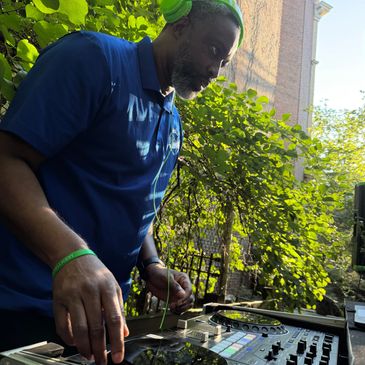 Man DJing outdoors with headphones on.
