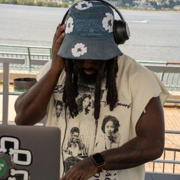 DJ wearing headphones and a floral bucket hat.
