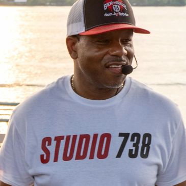 Man wearing a Studio 738 shirt and cap with a microphone headset.