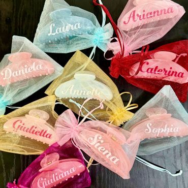 Colorful personalized organza bags with names and hair clips.