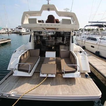 Modern sailboat with spacious deck seating docked at marina.