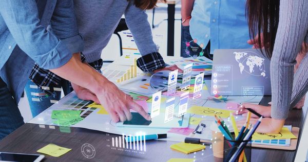 Two people collaborate on a digital project, analyzing data visuals and sticky notes on a table