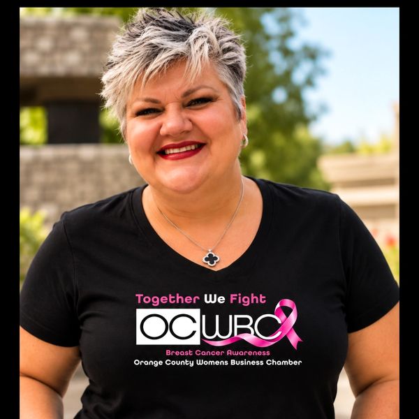 Woman wearing a breast cancer awareness shirt smiling.