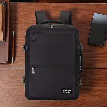Sleek black British Traveller backpack on wooden desk with notebook, pen, and smartphone.