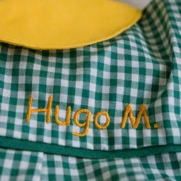 Green checkered fabric with embroidered name "Hugo M."