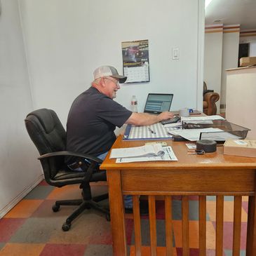Man working at a cluttered wooden desk in an office.
