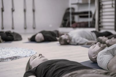 People lying down on yoga mats in a calm indoor setting.