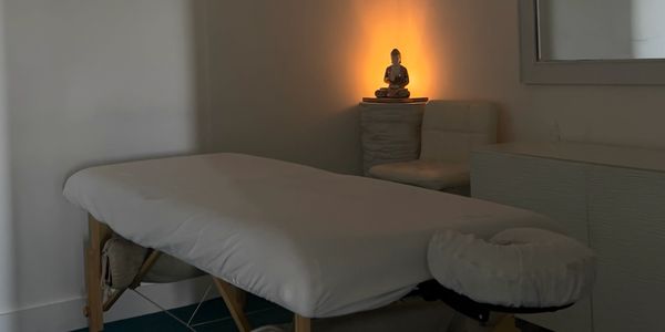 Serene massage room with a lit Buddha statue creating a calming ambiance.