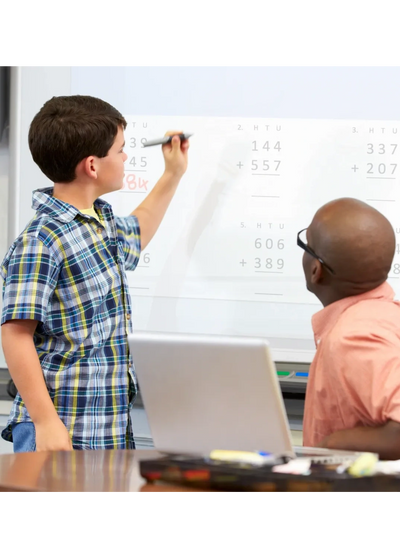 Tutor teaching a young boy on a white board.