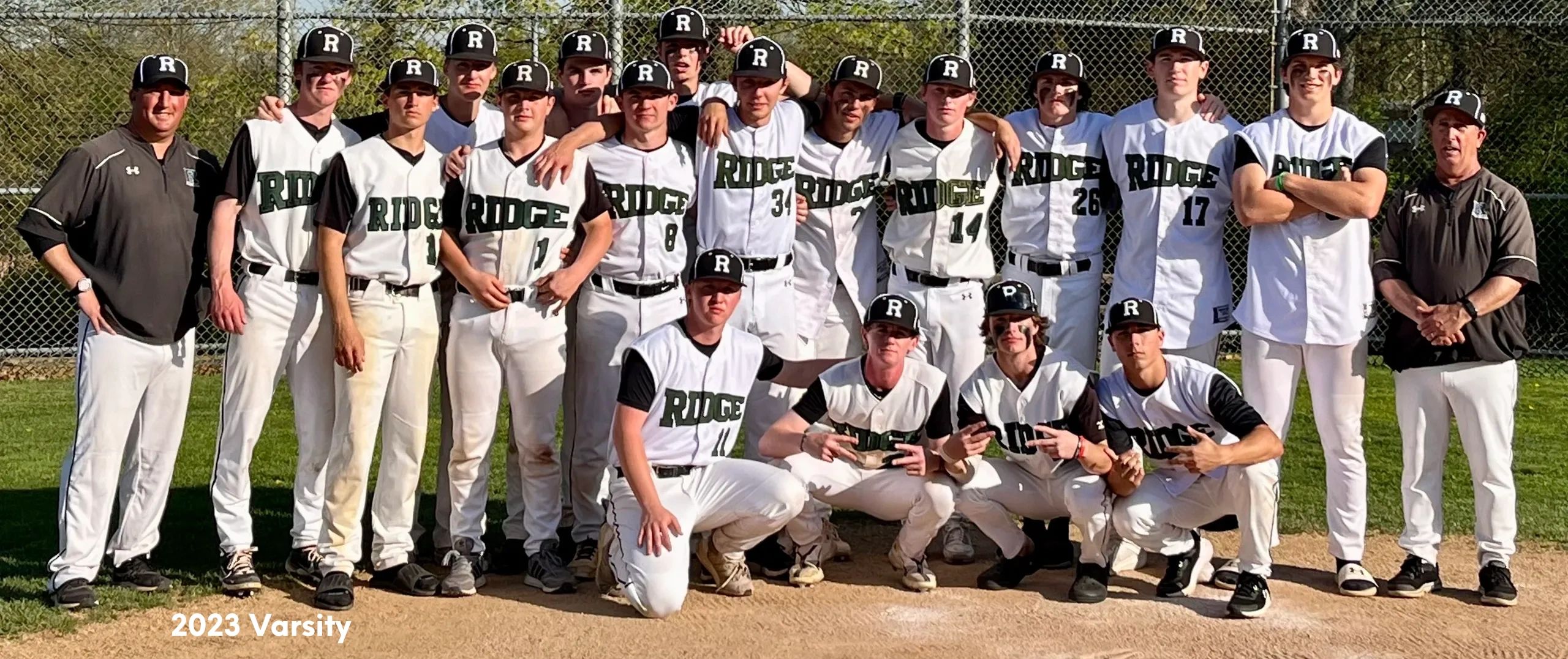 2023 varsity baseball team posing together on a baseball field.