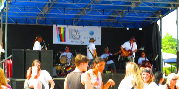 People enjoying music at an outdoor pride event.