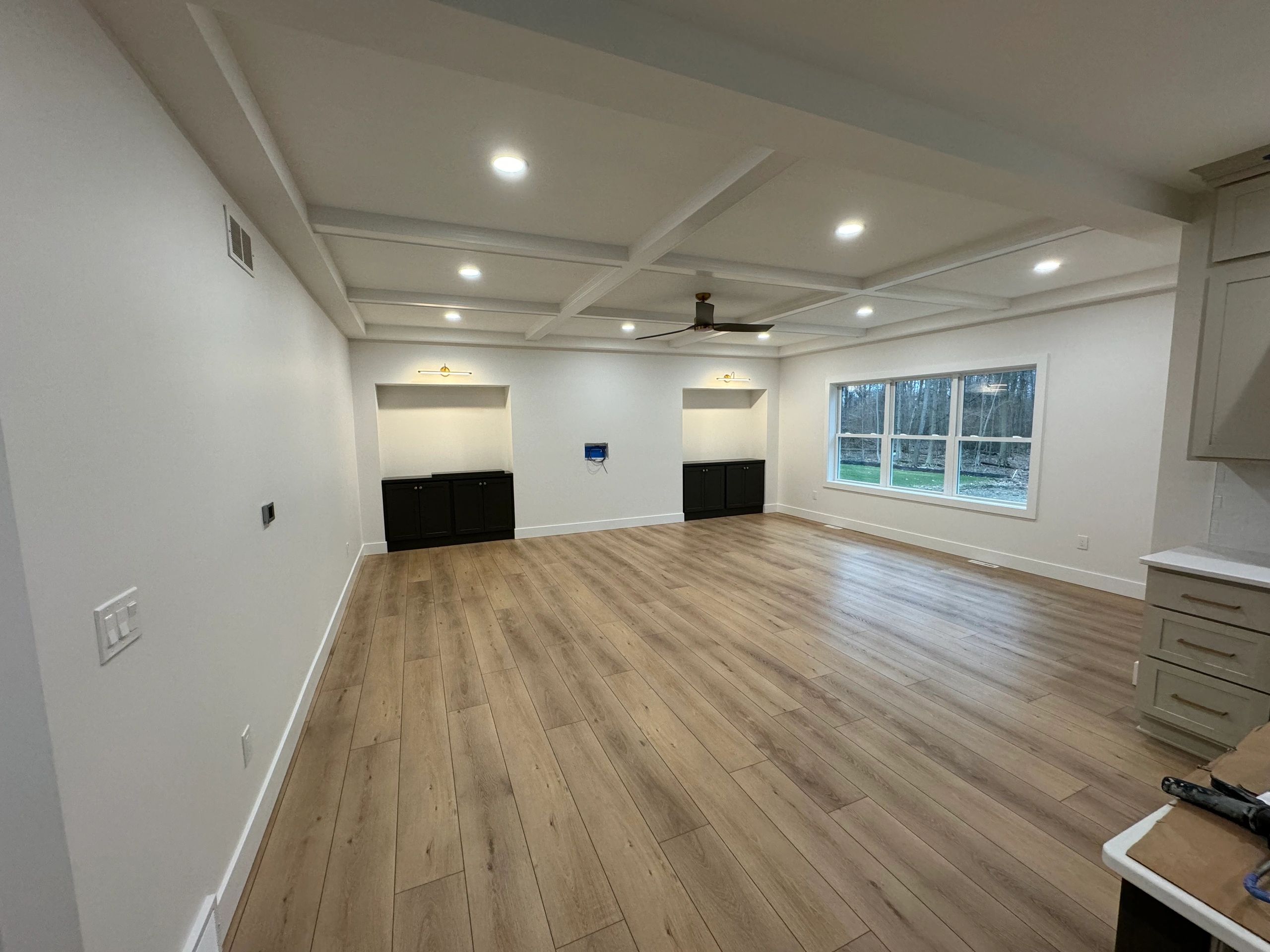 Empty modern living room with wood floors and ceiling fan.