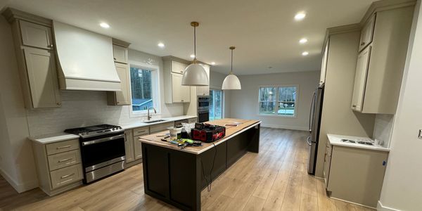 Modern kitchen with wooden flooring and pendant lights.