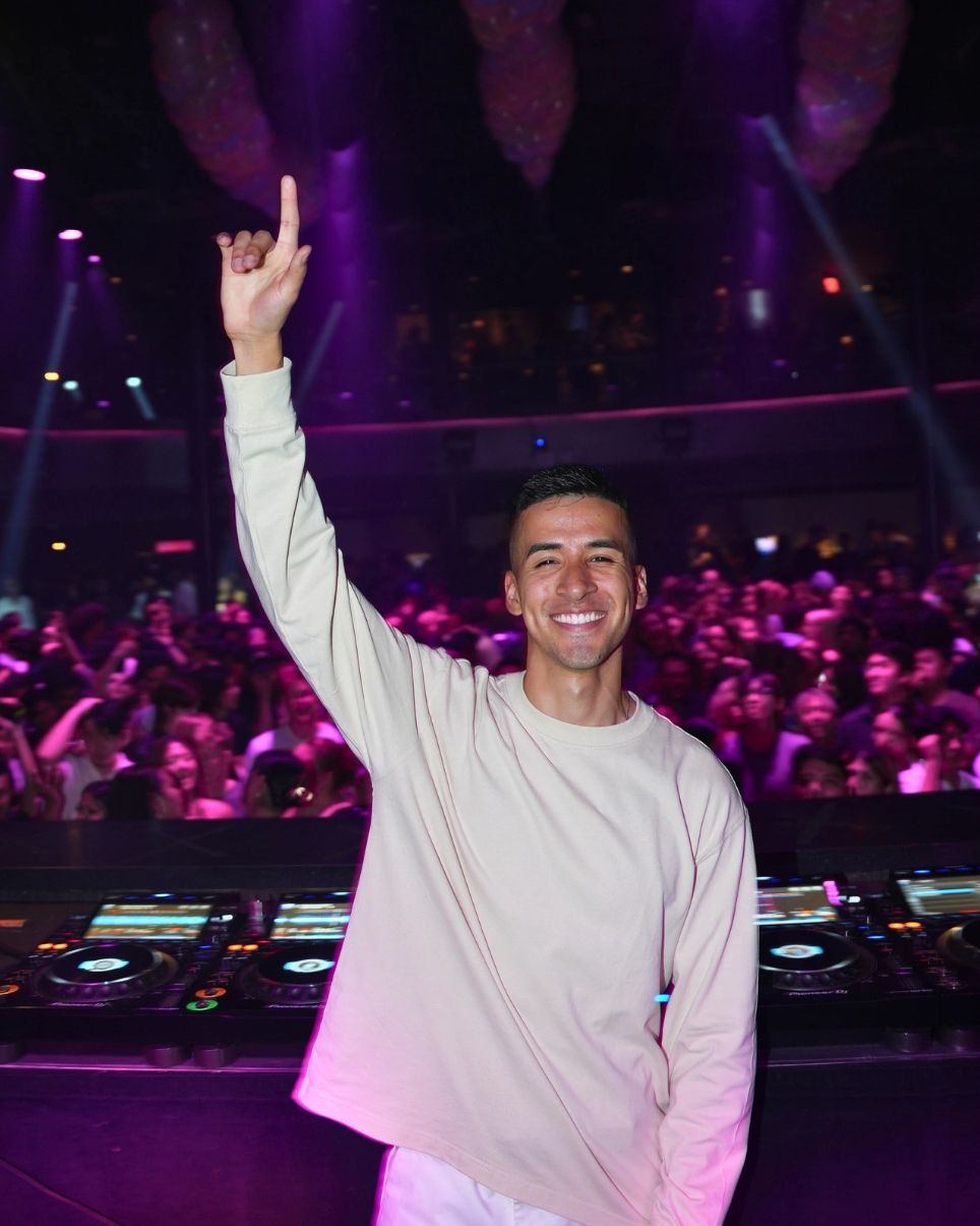 DJ Rollintino performing live behind the decks for a packed crowd with vibrant lighting.