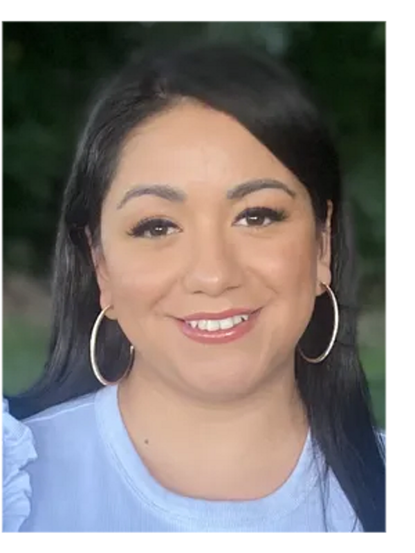 Woman with hoop earrings smiling outdoors.