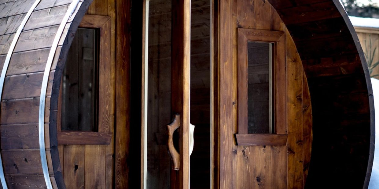 Old wood sauna barrel, with two glass windows and glass door. In winter months with visible snow