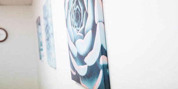 Close-up of a blue rose painting hanging on a white wall.
