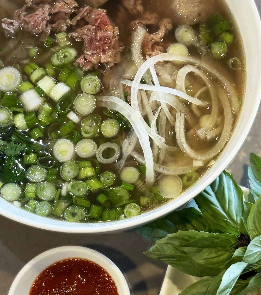 Piping Hot Bowl of Vietnamese Pho with sauce and sides.