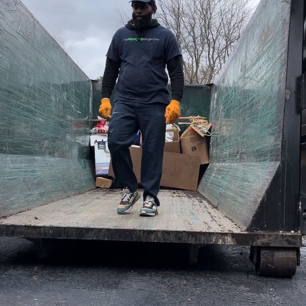 A crew member loading a dumpster 