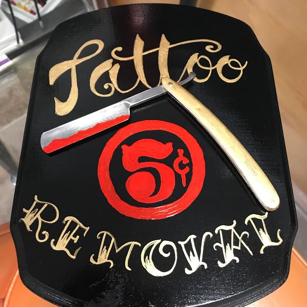 Vintage sign advertising tattoo removal for 5 cents with a razor illustration.