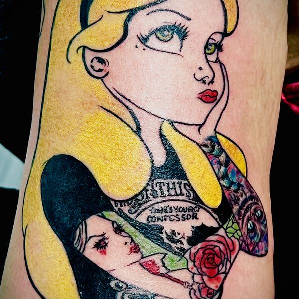 Colorful tattoo of a blonde woman with intricate designs on her arm.