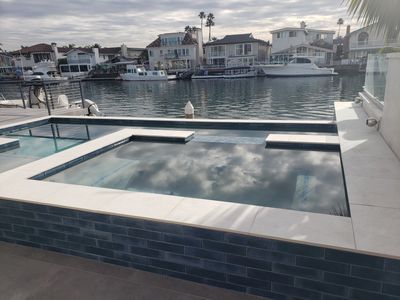 Waterfront pool and spa with dark tile waterline and gray decking