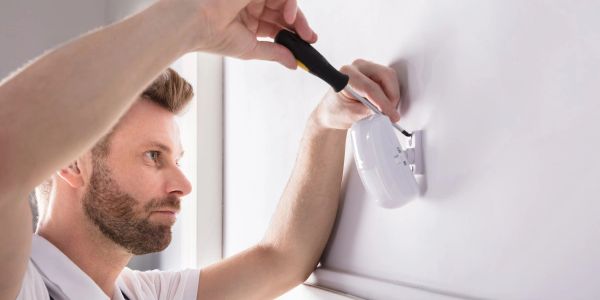 Technician installing alarm-system equipment