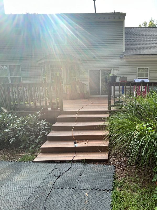 Outdoor deck stairs with sunlight and garden.