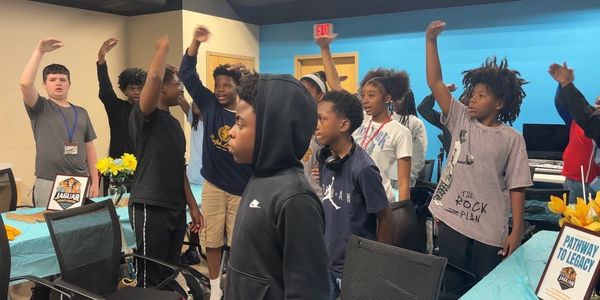 A group of children raising their hands in a classroom setting.