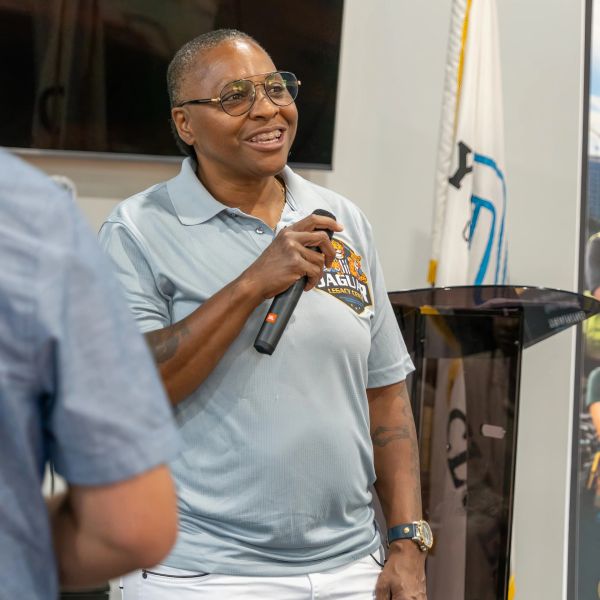 Person smiling and speaking into a microphone indoors.