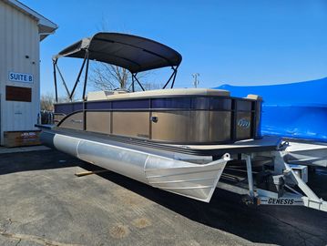 Pontoon boat on trailer outside a building.