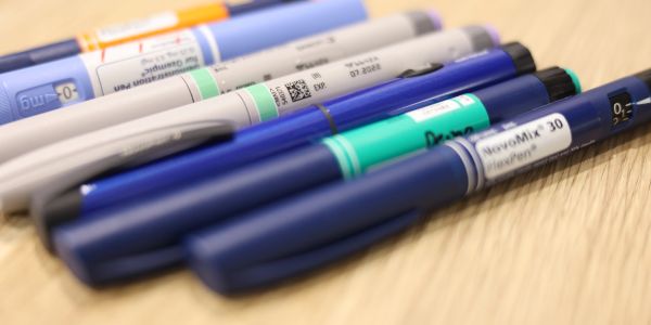 A row of insulin pens on a wooden surface.