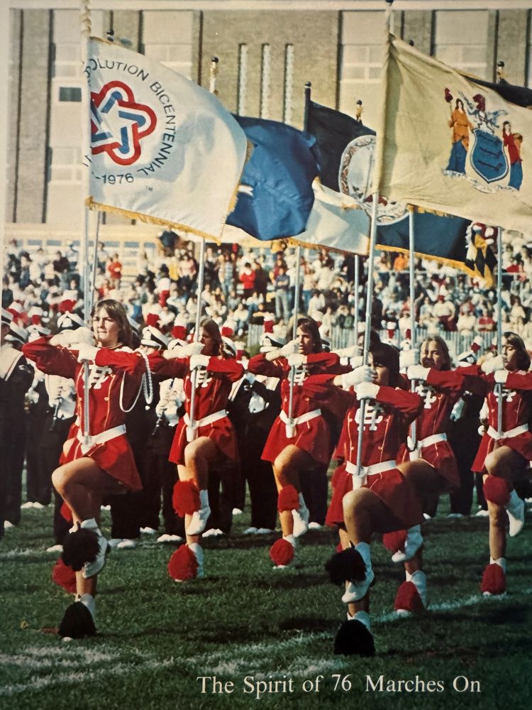 Stack of books next to pencils in a holder and a camera.