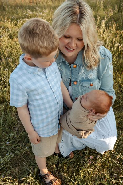 Mom with her son and newborn baby in a field during their lifestyle newborn session