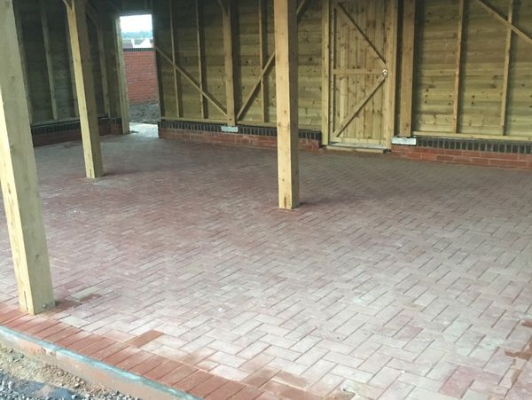 Newly laid brick flooring inside a wooden structure with supporting beams.