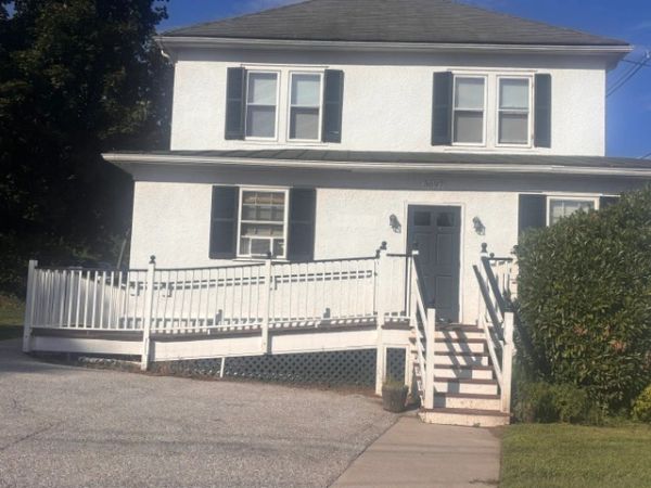 White house with black shutters and wheelchair ramp.