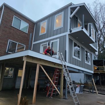 A man working on the deck of a two-story house under construction.