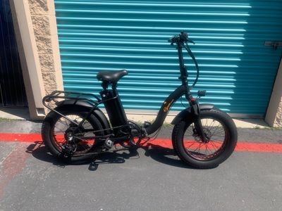 Black electric bike parked near a blue shutter door in sunlight.