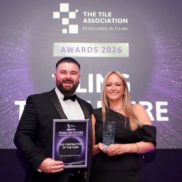 Two people holding awards at a tiling association event.
