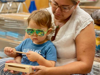 mother helping child play wood block